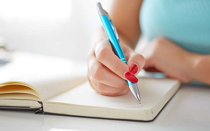 Pessoa escrevendo em um bloco de notas Pessoa escrevendo em um bloco de notas
