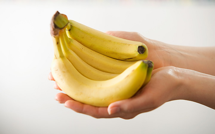 Pessoa segurando uma penca de banana
