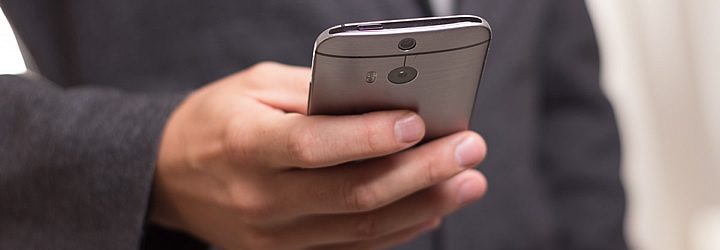 Pessoa segurando um celular - Dicas para usar o celular no exterior Pessoa segurando um celular - Dicas para usar o celular no exterior