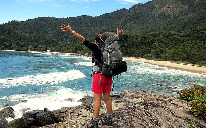 Trilhas em Ilha Grande Mochileiro em uma pedra em frente ao mar