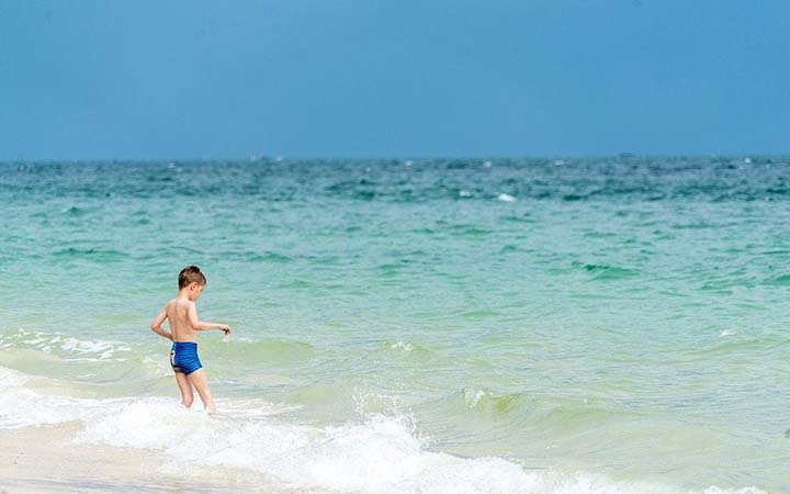 Criança na orla da praia Criança na orla da praia