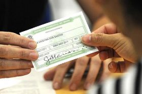 Pessoa entregando o título de eleitor - Justificar o voto no exterior