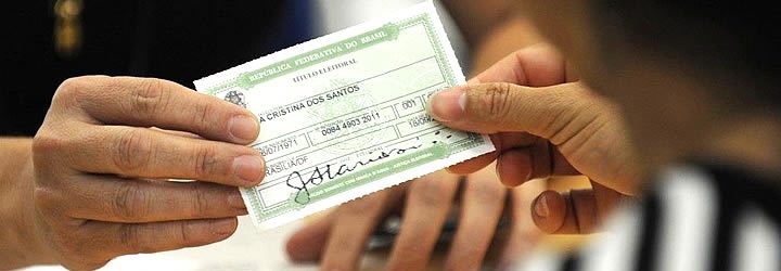 Pessoa entregando o título de eleitor - Justificar o voto no exterior Pessoa entregando o título de eleitor - Justificar o voto no exterior