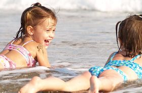 Duas crianças deitada na areia da praia