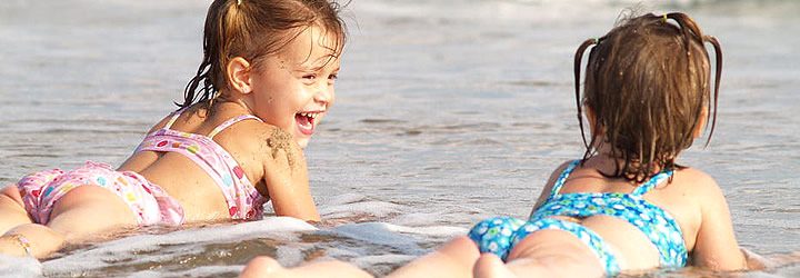 Duas crianças deitada na areia da praia Duas crianças deitada na areia da praia