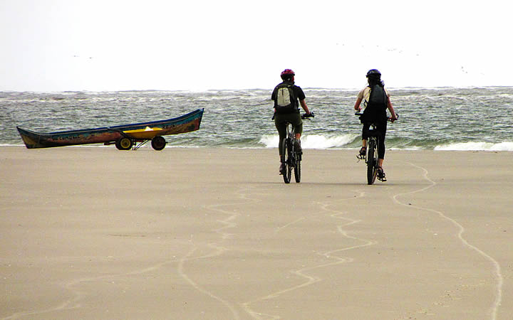 Duas pessoas pedalando na Praia deserta da Ilha de Superagui Duas pessoas pedalando na Praia deserta da Ilha de Superagui