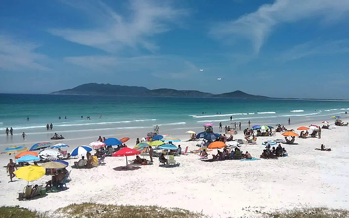 Pessoas sentadas tomando sol na Praia das Dunas em Cabo Frio Pessoas sentadas tomando sol na Praia das Dunas em Cabo Frio