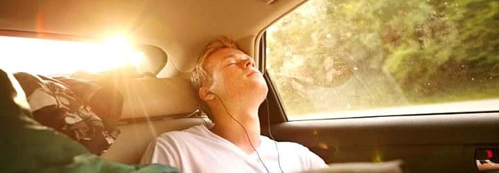 Rapaz dormindo no carro e ouvindo música durante a viagem longa Rapaz dormindo no carro e ouvindo música durante a viagem longa