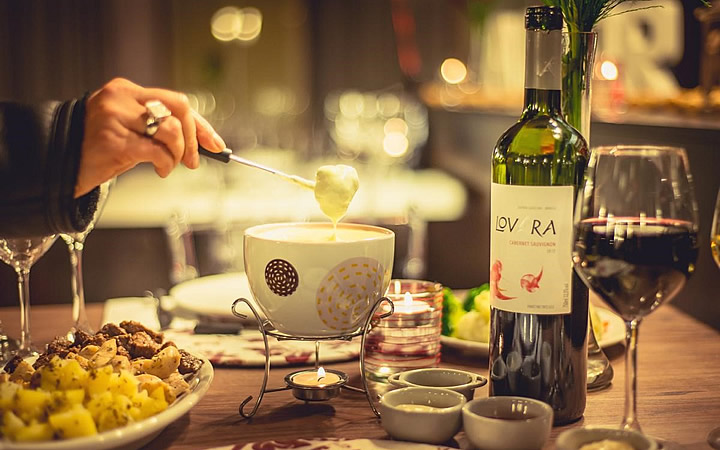 Mesa com refeições e uma garrafa de vinho da Vinícola Lovara Mesa com refeições e uma garrafa de vinho da Vinícola Lovara