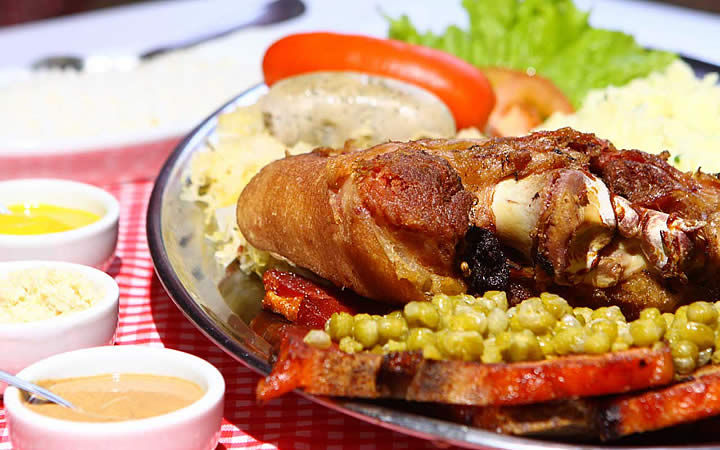 Prato de comida com frango, ervilha, arroz e molhos ao lado - Gastronomia de Pomerode