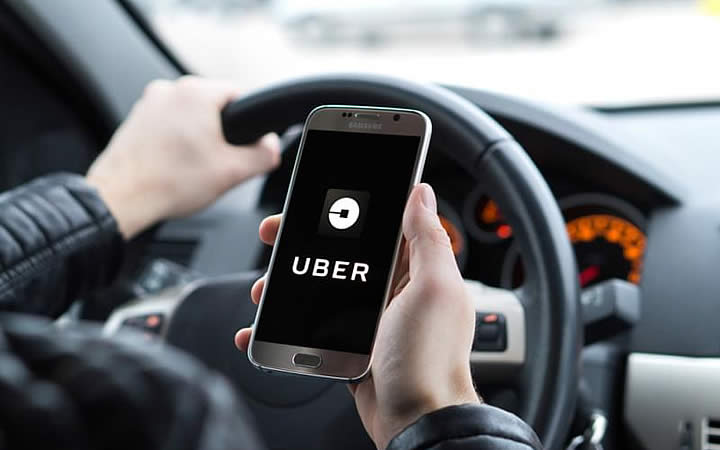 Homem segurando telefone com o app do Uber Homem segurando telefone com o app do Uber