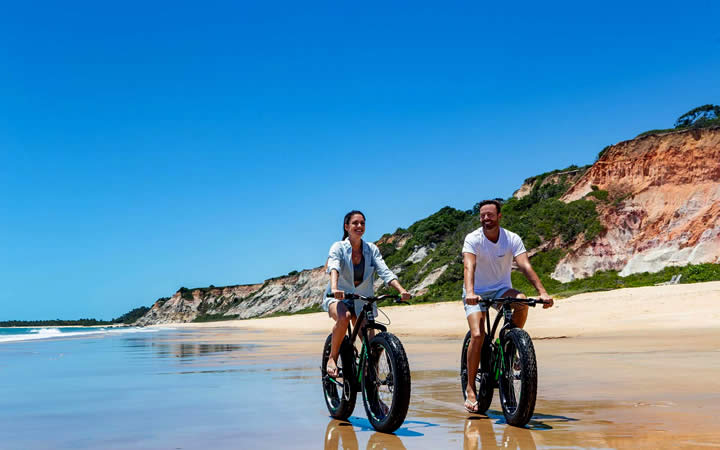 Pessoas andando de bicicleta na praia Pessoas andando de bicicleta na praia